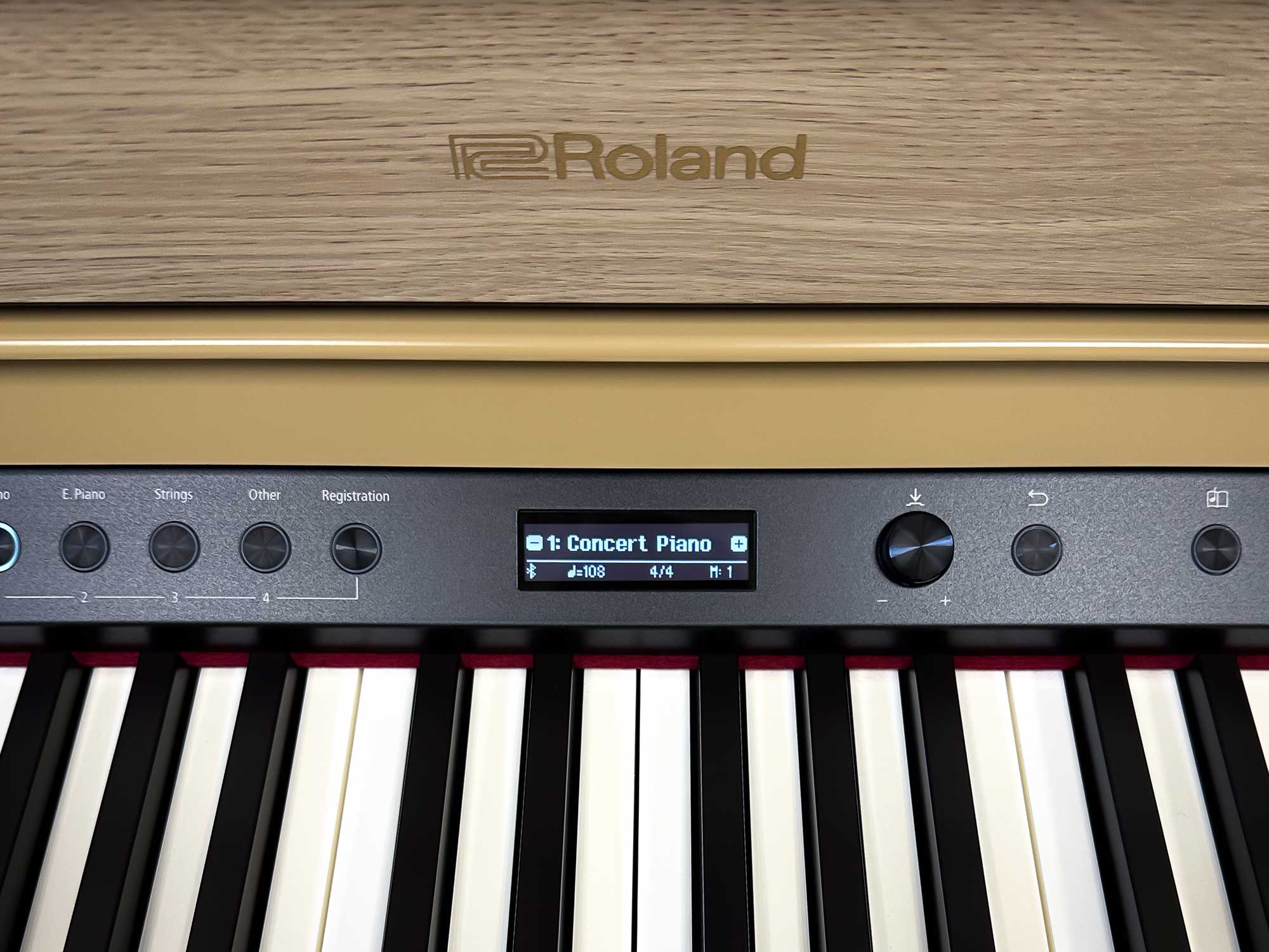 Closeup on keys and display screen of Roland HP702 in Light Oak finish