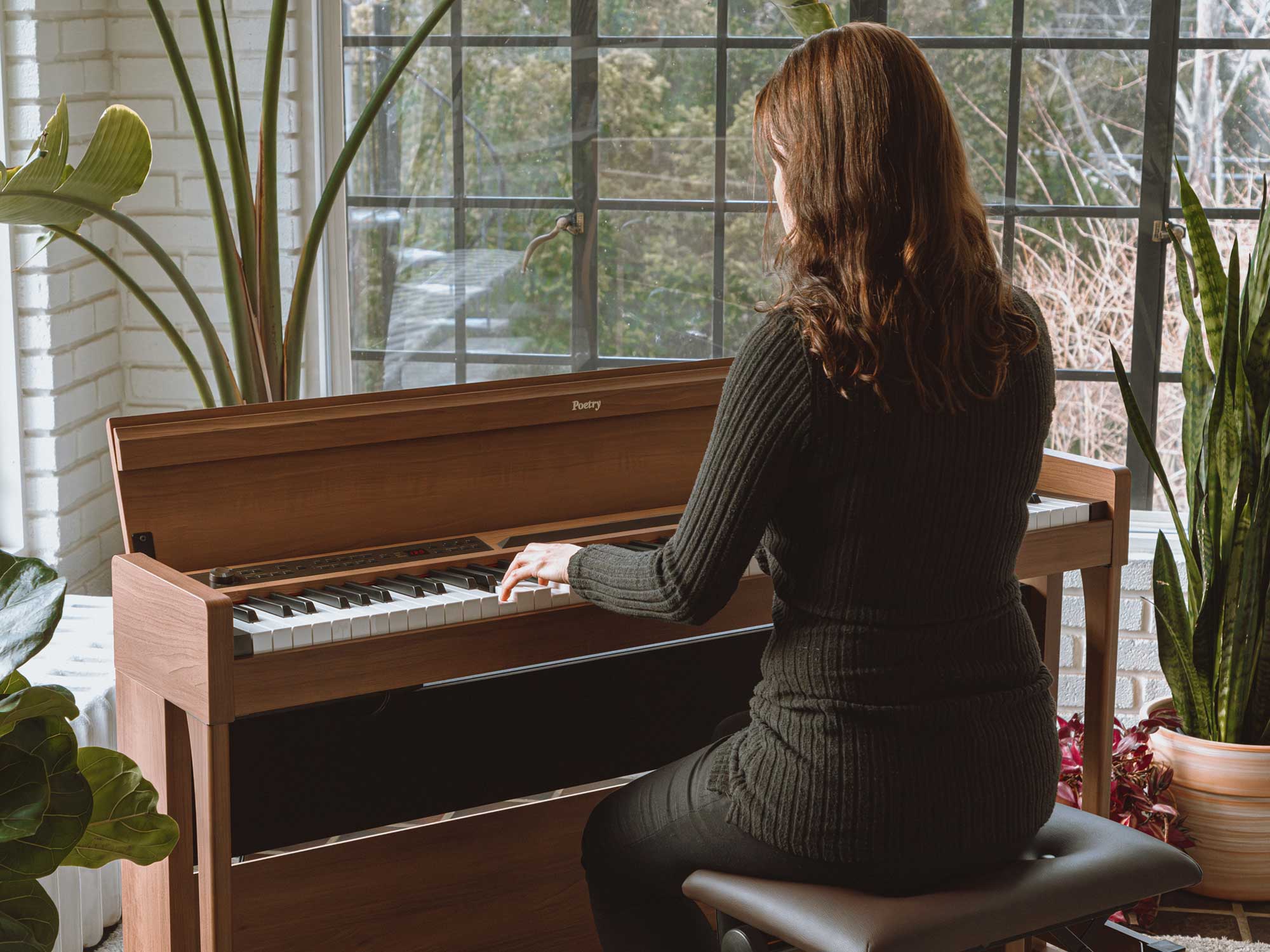 Over the shoulder view of woman playing Korg Poetry piano in a home setting