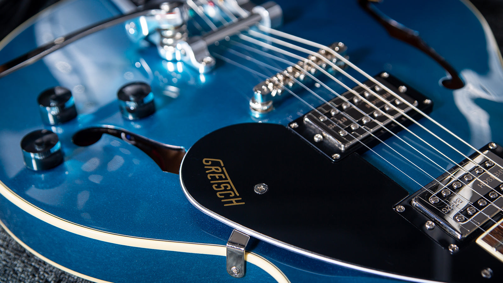 A Gretsch hollow body guitar lying on a rug