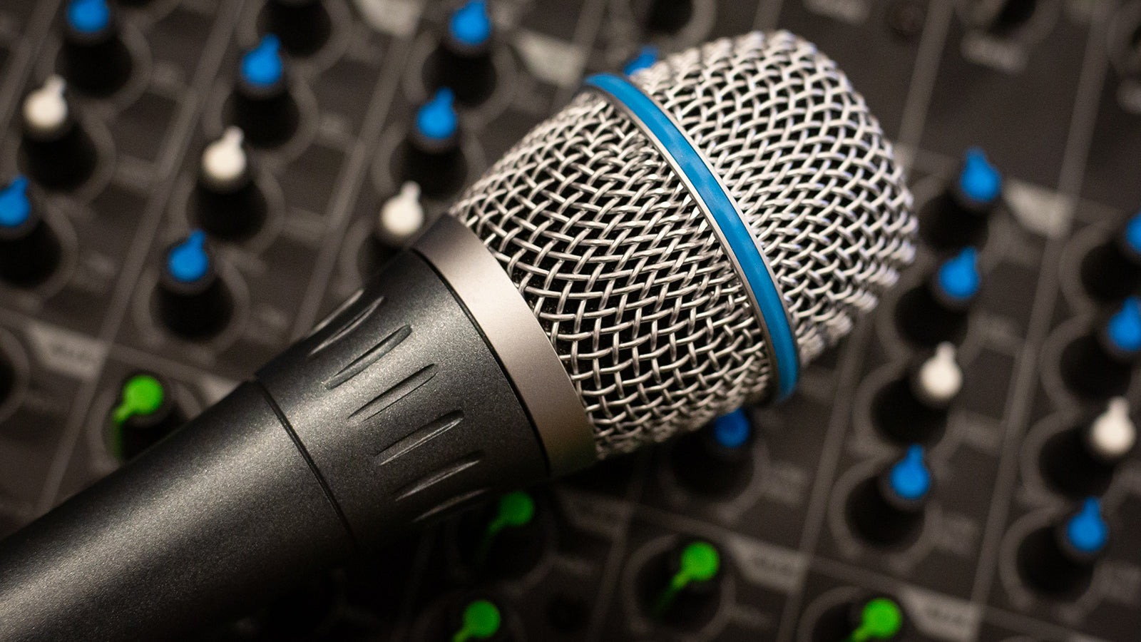 A Shure vocal microphone resting on a mixing console