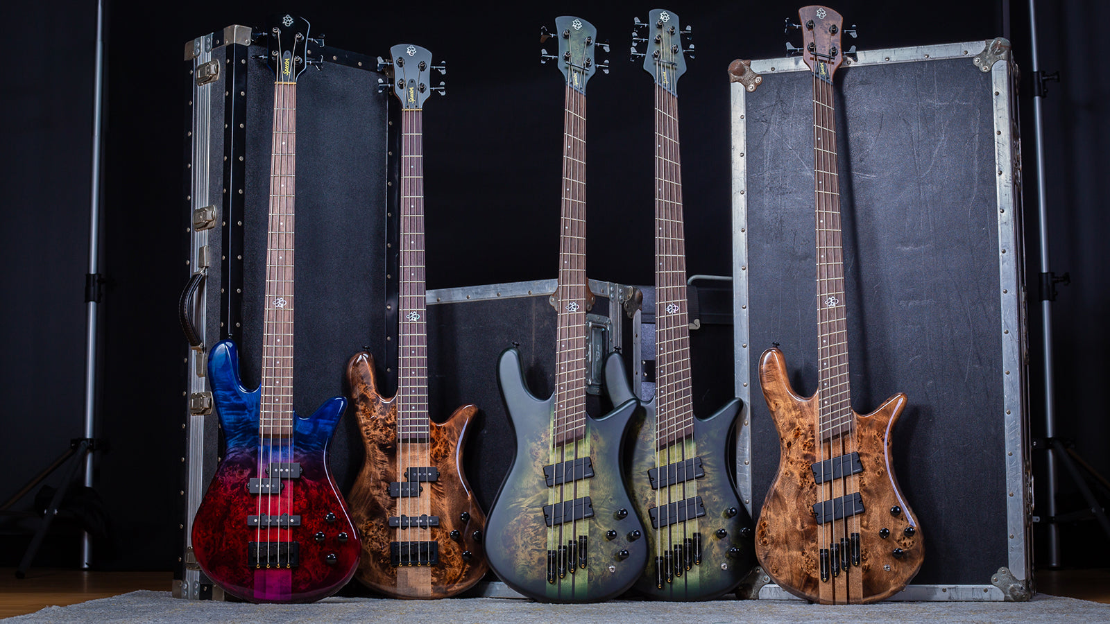 A collection of Spector basses lined up in front of some road cases