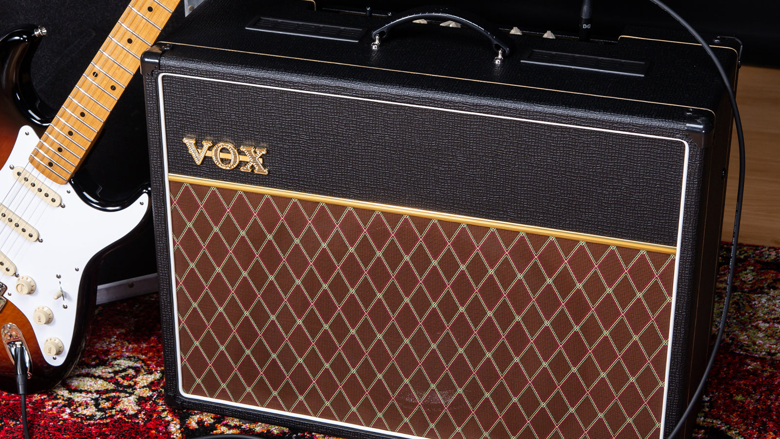 A guitar leaning against a VOX amplifier