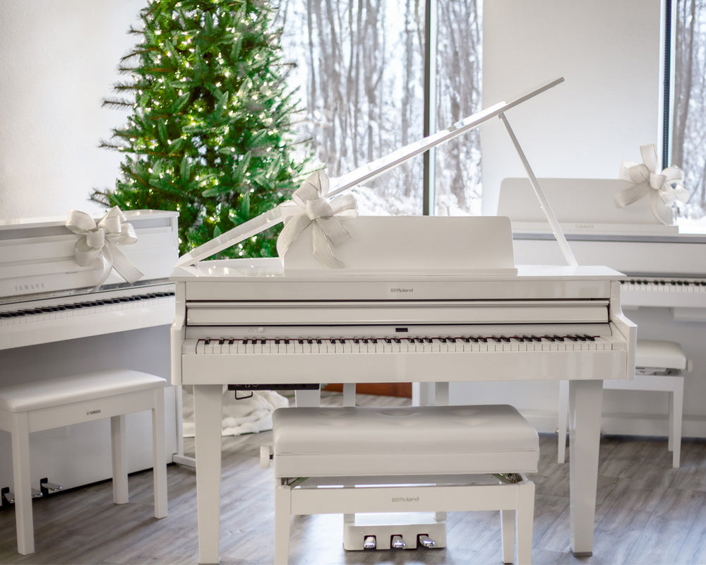 Image of white Yamaha, Roland And Casio digital pianos with christmas tree in the background