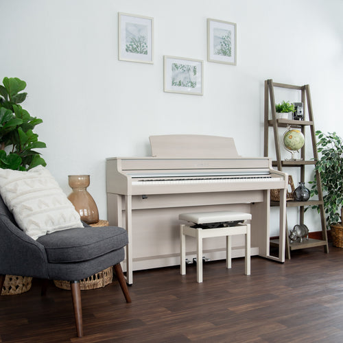 Kawai CA501 Concert Artist Digital Piano - White Maple in a room with a gray armchair, plant, and decorative items.