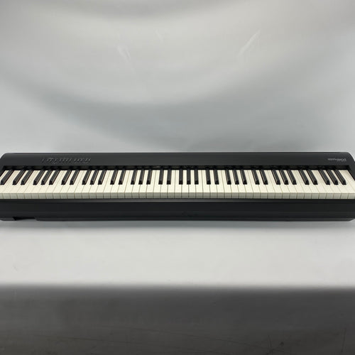 A Roland digital piano shown from the front against a neutral gray fabric backdrop.