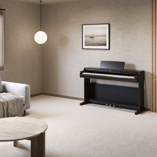 Modern living room with a rosewood digital piano, gray sofa, and round wooden table.