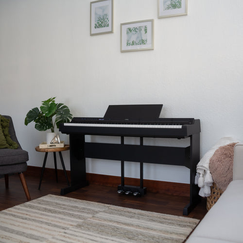Yamaha P-S500B Digital Piano with L-300B Stand and LP-1B Triple Pedal - Black - in a living room setting with a couch, chair, and decor items.