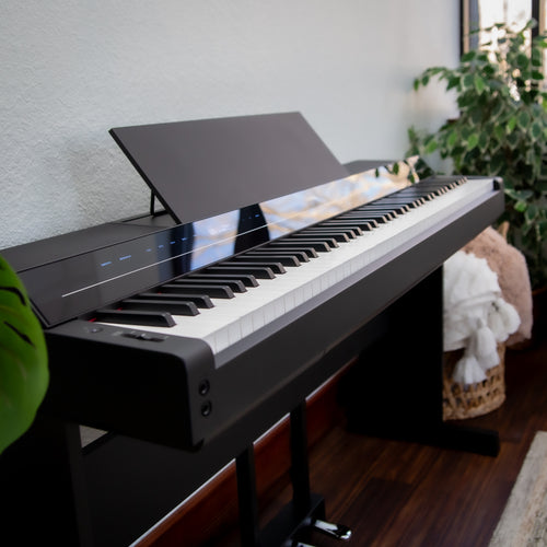 Yamaha P-S500B Digital Piano with L-300B Stand and LP-1B Triple Pedal - Black - in a room with a plant and basket in the background