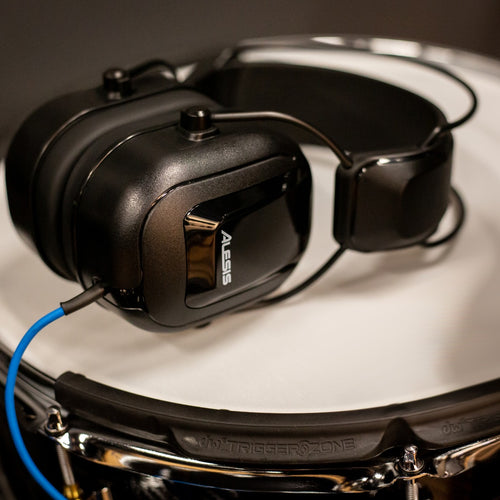 View of the Alesis DRP100 Electronic Drum Reference Headphones laying on their side on the head of an electronic snare drum