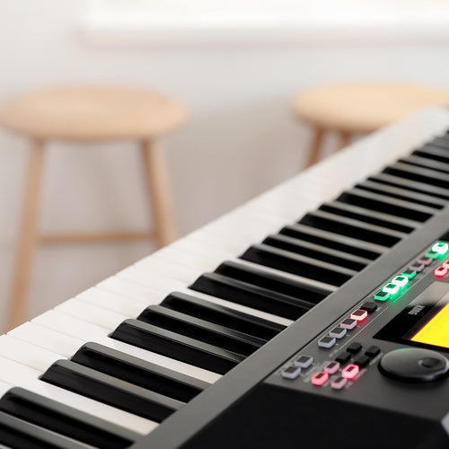 Lifestyle image of Korg XE20 Home Digital Ensemble Piano with keybed and control panel in foreground and wooden stools in background