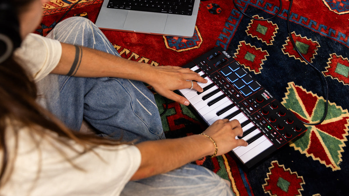A young lady playing a Akai Professional MPK Mini keyboard
