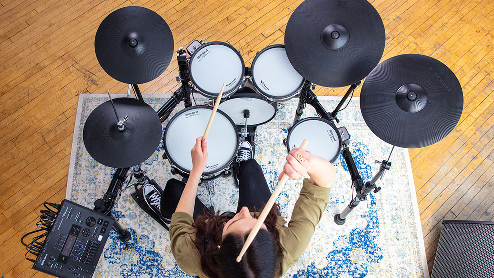 A view from above of a young lady playing a Roland TD-50K2 drum set