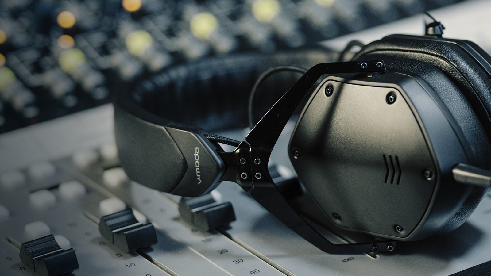 A pair of V-Moda headphones on a mixing console in a recording studio