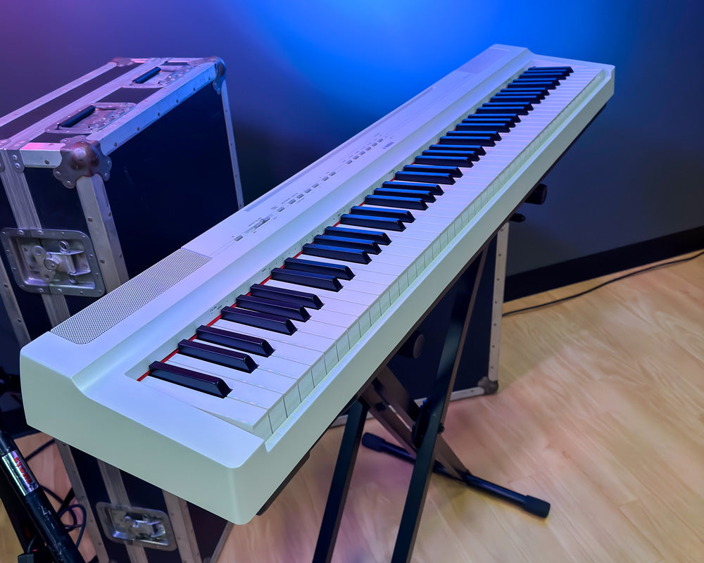 Yamaha P-125a in white finish in front of a blue lit wall