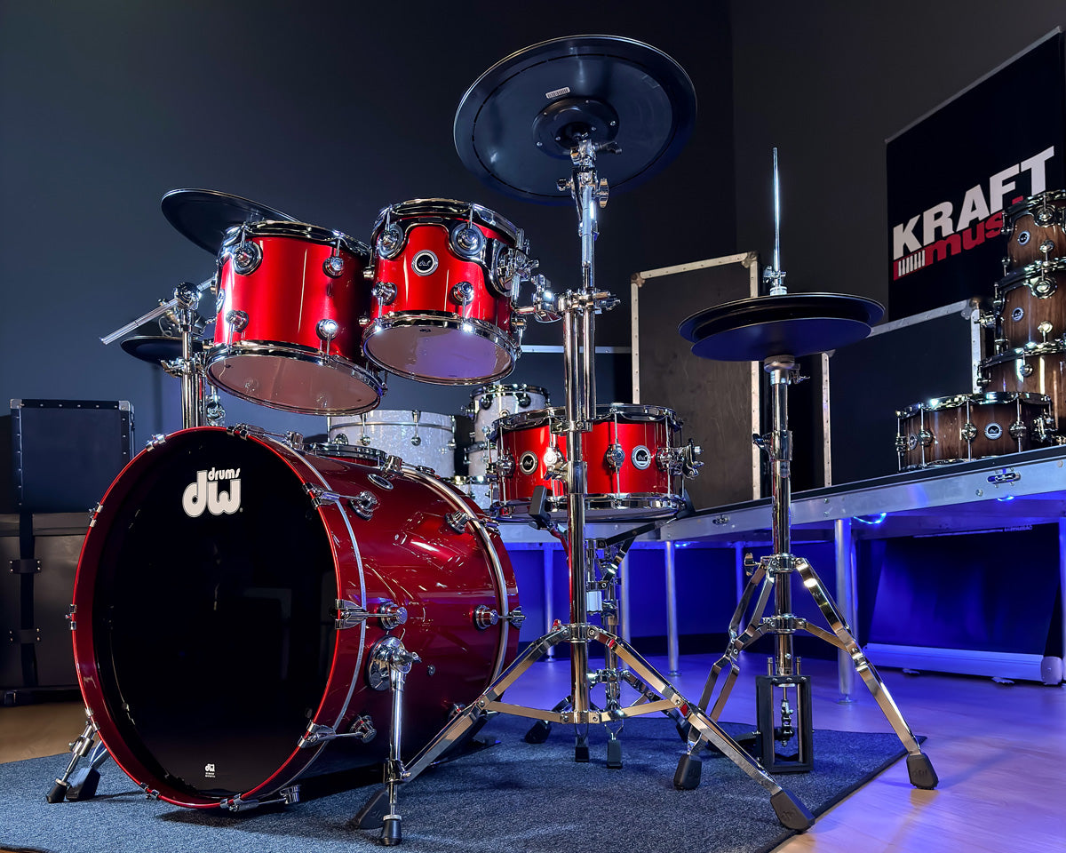 Red DWe drum set with white drums stacked in the background and blue ambient lighting