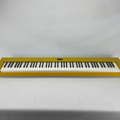 A digital piano keyboard with a metallic gold body and black and white keys, photographed against a plain light gray background.