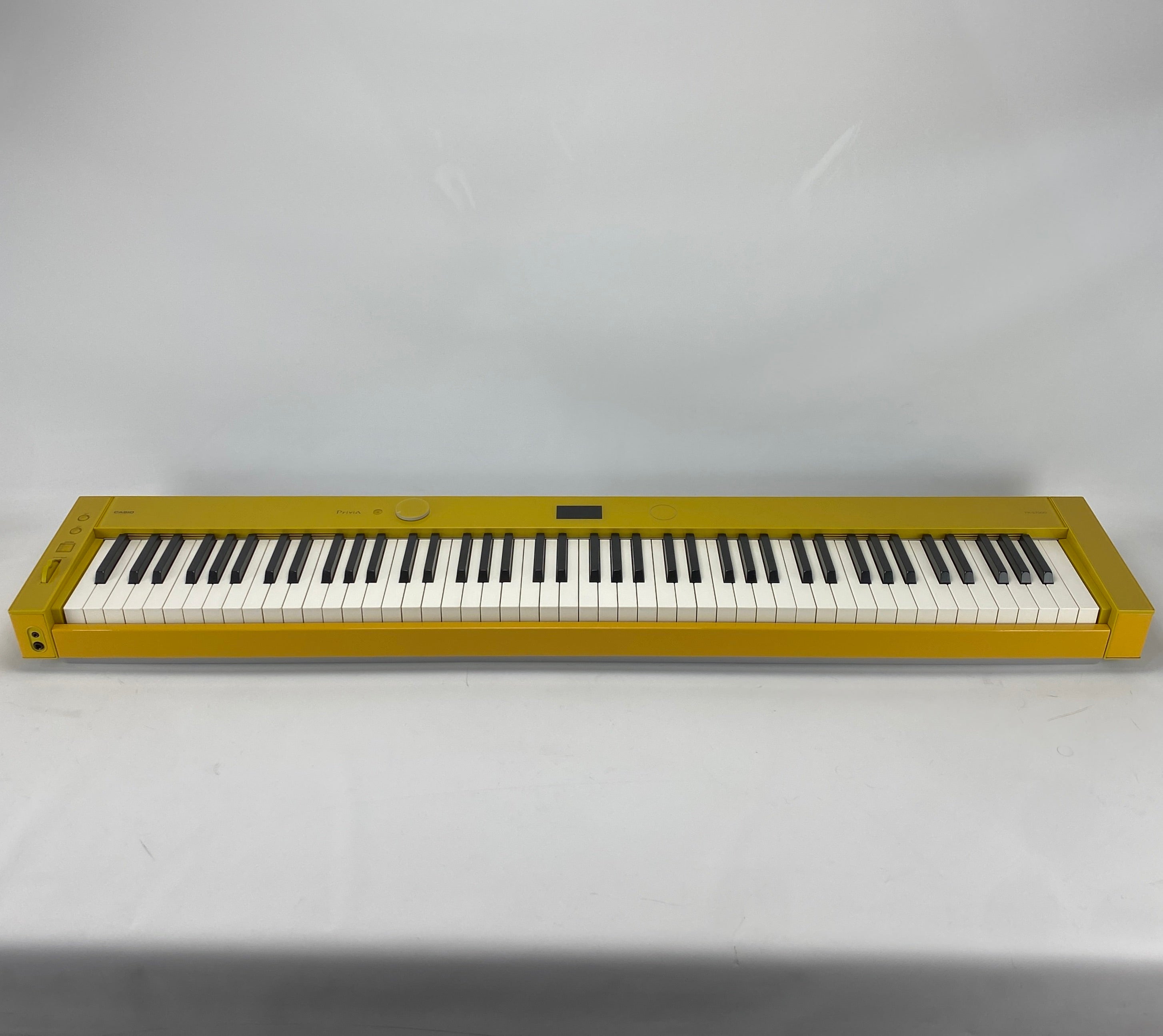 A digital piano keyboard with a metallic gold body and black and white keys, photographed against a plain light gray background.
