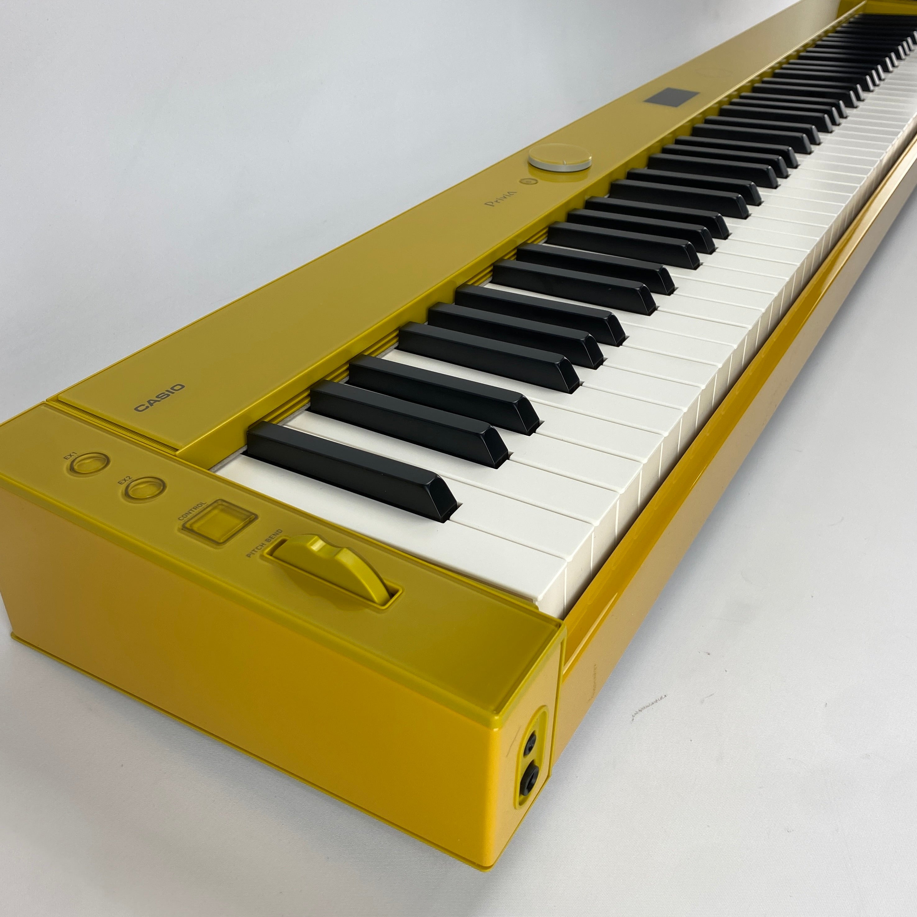 A Casio keyboard in a metallic gold finish, featuring black and white keys, photographed on a light gray background.