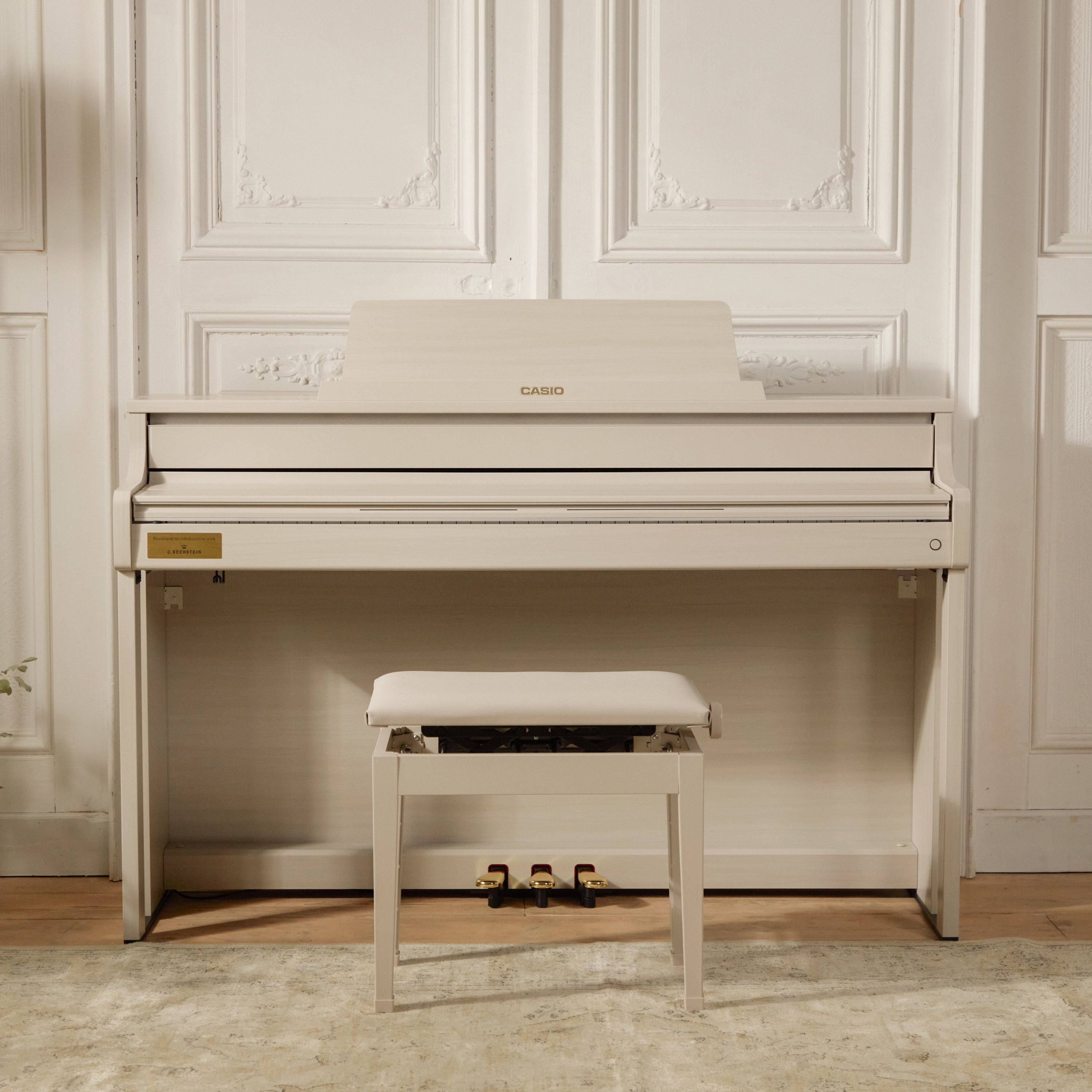 Casio Celviano AP-750 Digital Piano - Grey Beige with a bench in a room with white paneled walls.