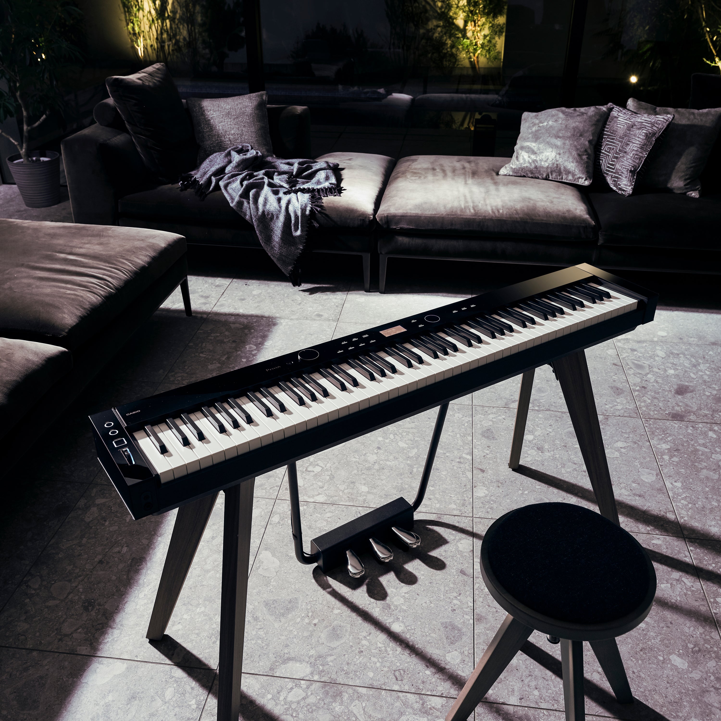 A black Casio PX-S7000 digital piano in a stylish living room