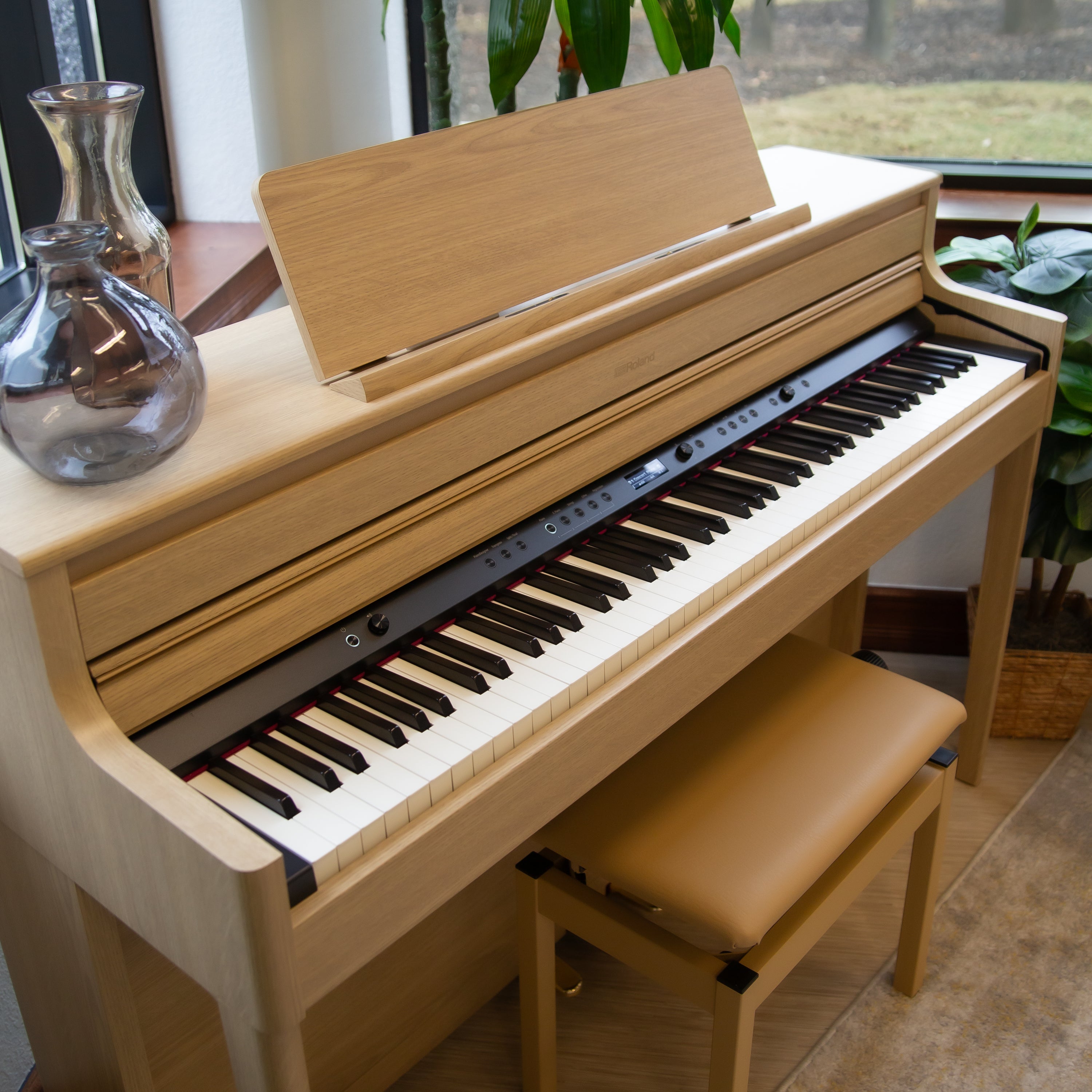 Roland HP704 Digital Piano - Light Oak with a bench in a room with plants and a window, showing the key cover open to show controls