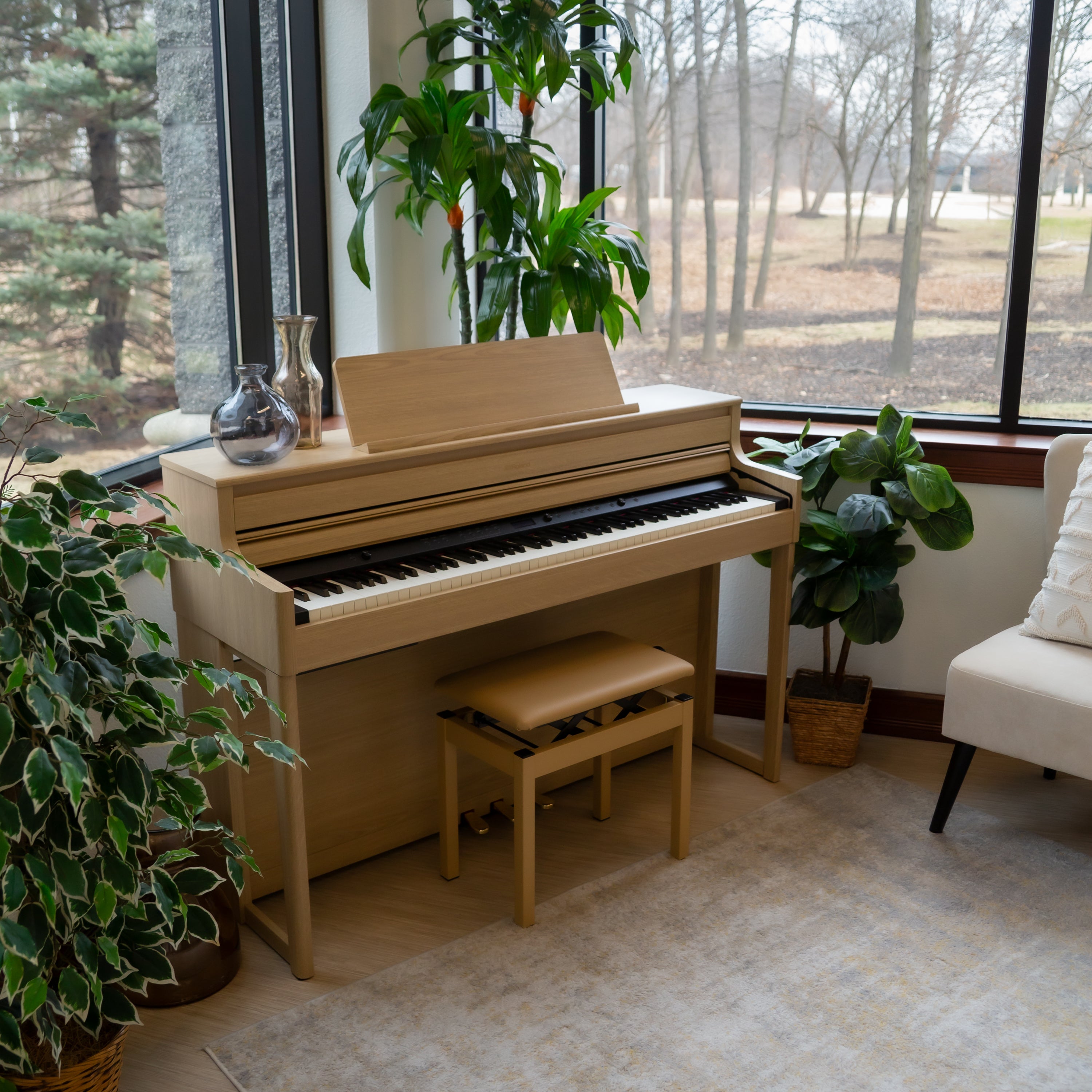 Roland HP704 Digital Piano - Light Oak in a room with large windows and indoor plants