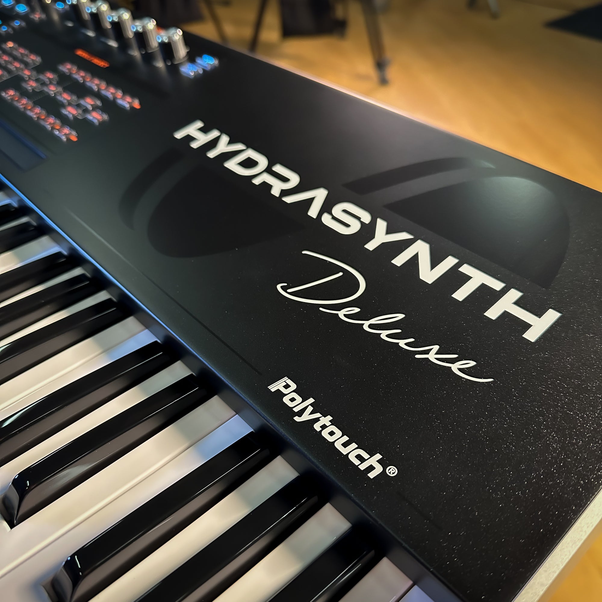 Close-up of a ASM Hydrasynth Deluxe showing the front control panel, white and black keys, and the model name in silver lettering.