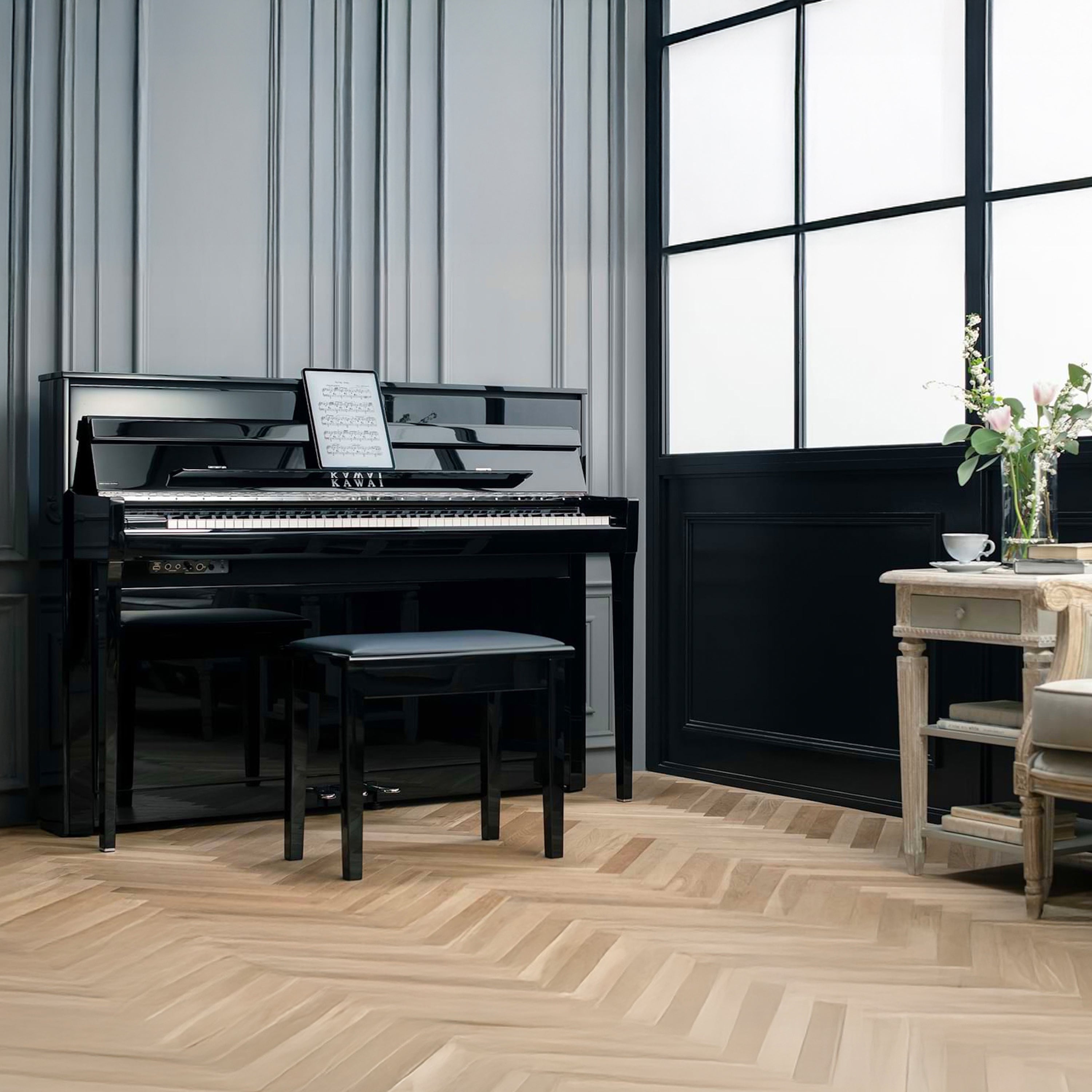 Kawai NOVUS NV6 Hybrid Upright Piano - Ebony Polish in a room with large windows and a wooden floor.
