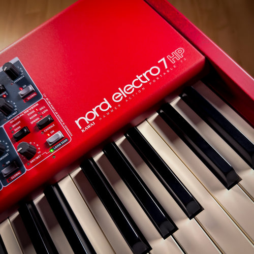 Red Nord Electro 7 HP keyboard with visible brand name on a wooden surface