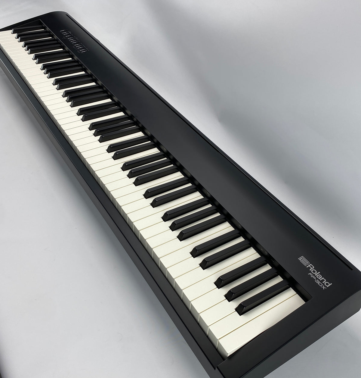 A Roland digital piano shown at an angle, featuring a black body, black and white keys, and the Roland logo on the side.