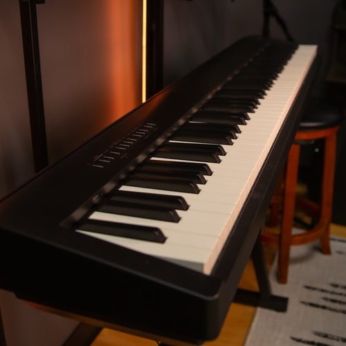 Roland FP-30X Digital Piano on a stand in a room with musical equipment.