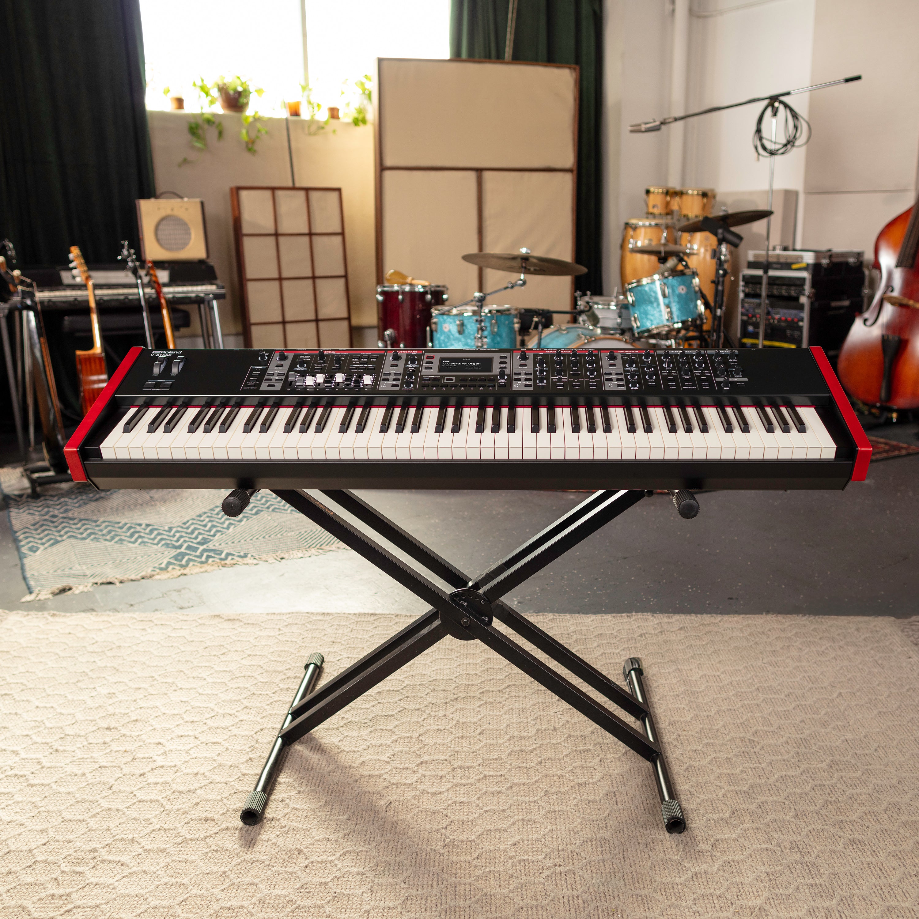 Roland V-Stage 88 Stage Keyboard on a stand in a music studio with musical instruments in the background