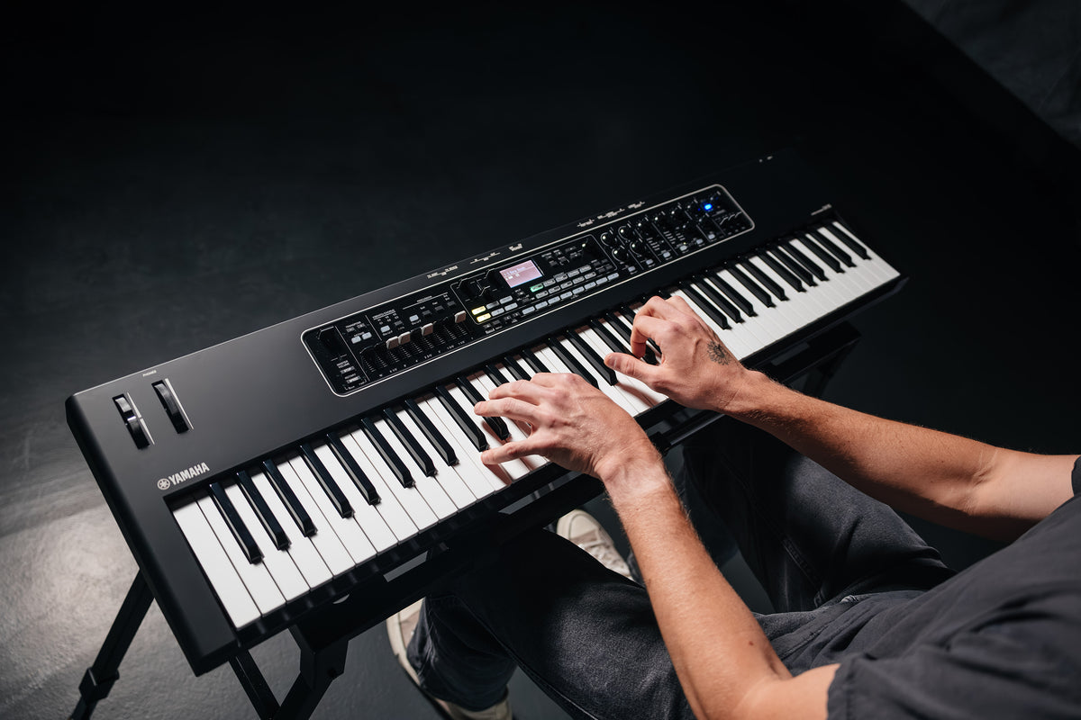 Overhead view of a musician playing the Yamaha CK76 stage keyboard on a stand