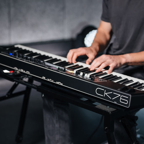 Musician playing the Yamaha CK76 stage keyboard on a stand, with the CK76 logo on the end panel in view
