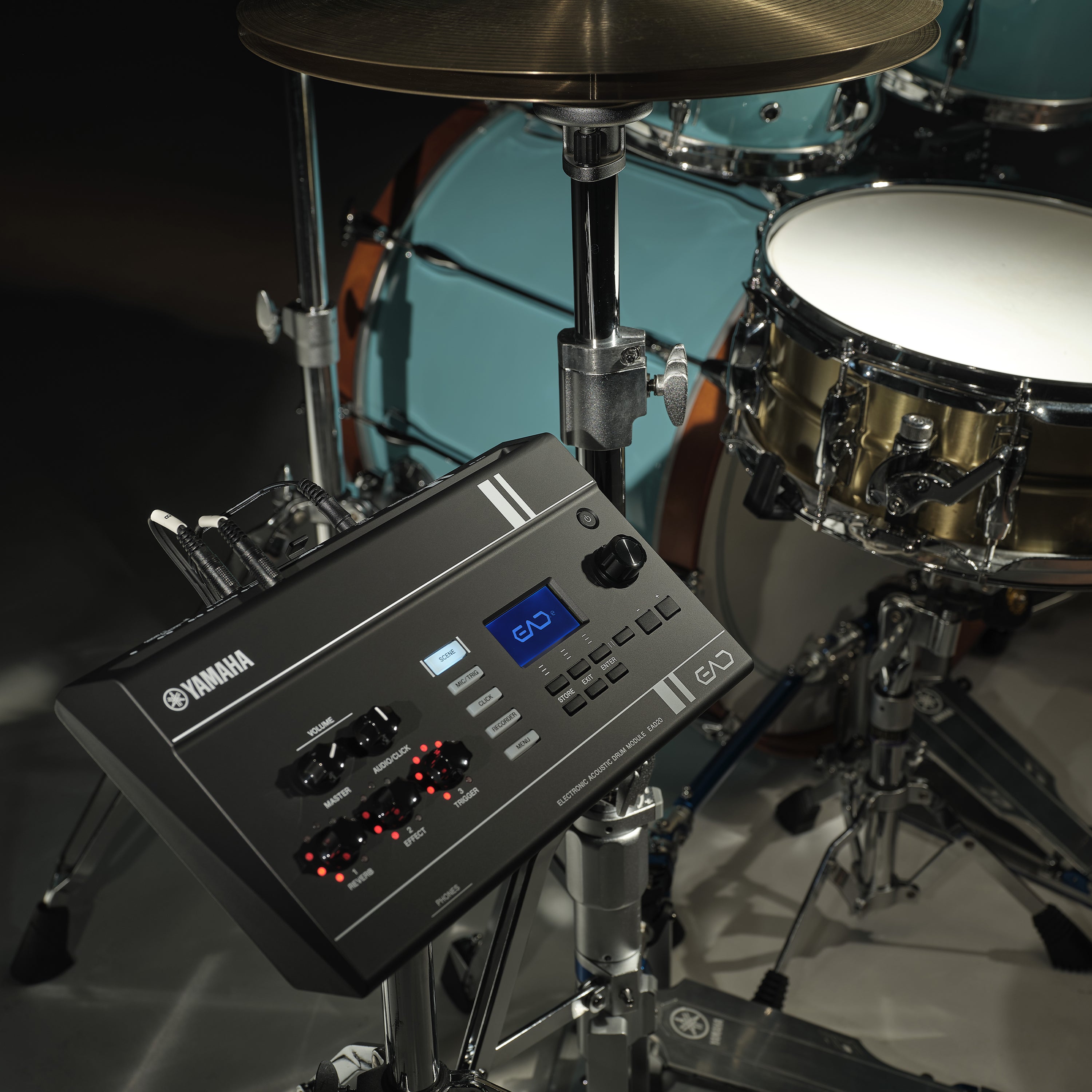 Yamaha EAD20 Electronic Acoustic Drum Module, shown in a studio setting with a drum set in the background.