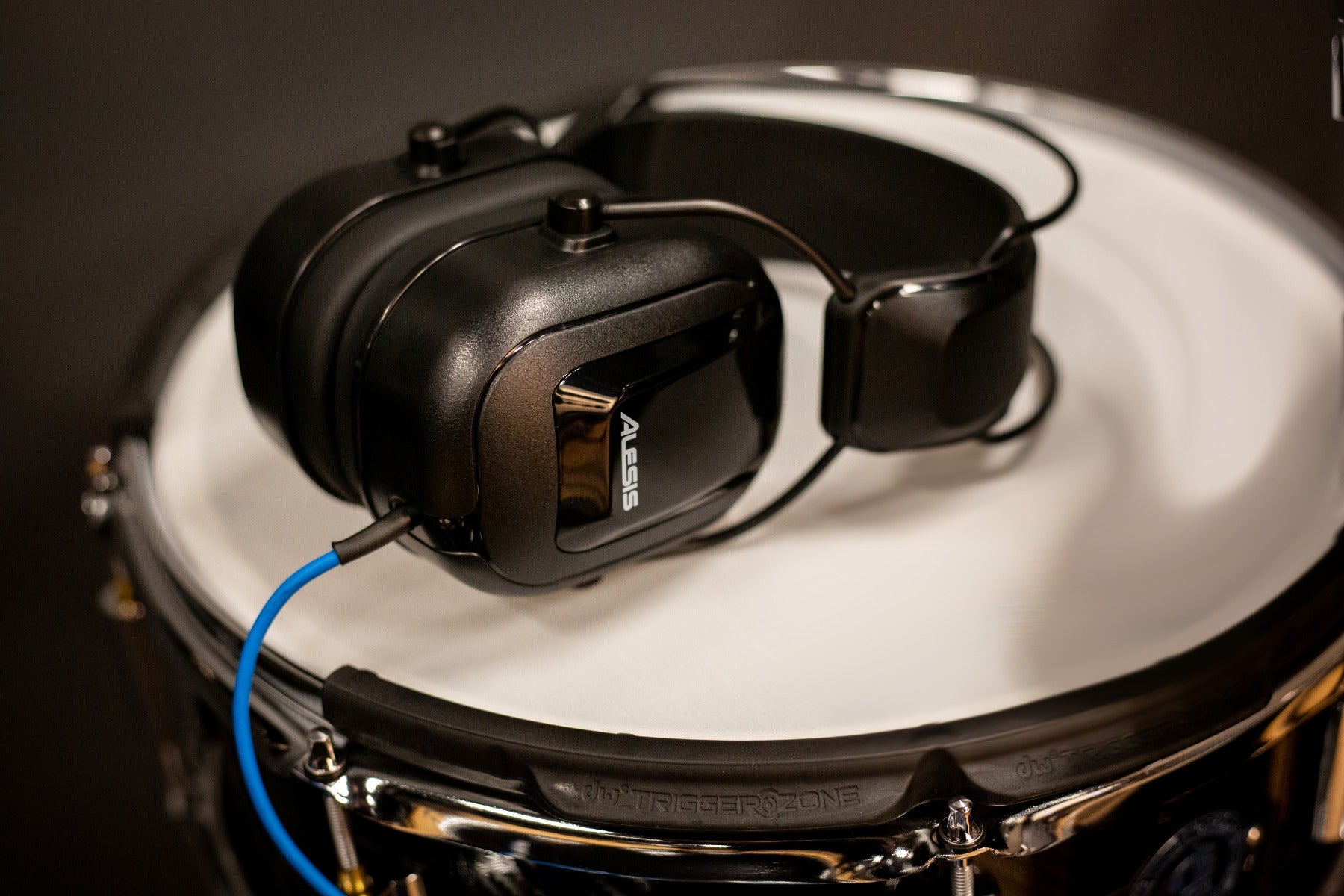 View of the Alesis DRP100 Electronic Drum Reference Headphones laying on their side on the head of an electronic snare drum