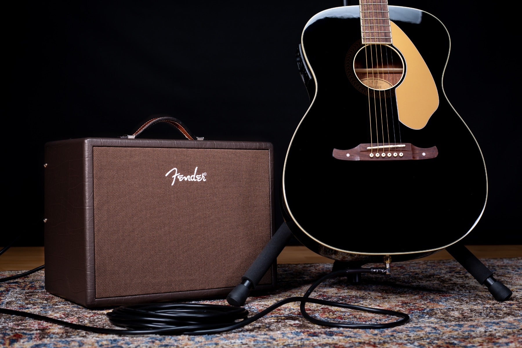 Front right angle view of the Fender Acoustic Junior Acoustic Guitar Amplifier on a rug with the Tim Armstrong guitar on a stand to the right