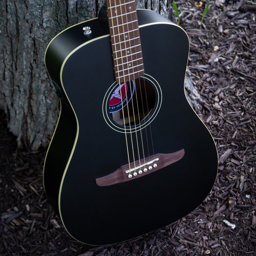 Style shot of the Fender Joe Strummer Campfire Acoustic Guitar leaning against a tree