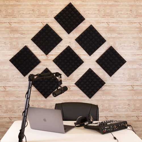 Lifestyle image of the acoustic foam panels mounted on a studio wall with a podcasting setup in front