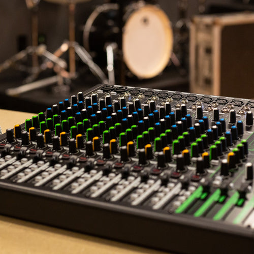 Right angle view of the Mackie ProFX16v3 Effects Mixer with USB on a work table at a gig with a microphone next to it